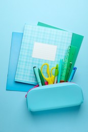 Photo of Copybooks and other school stationery on light blue background, flat lay