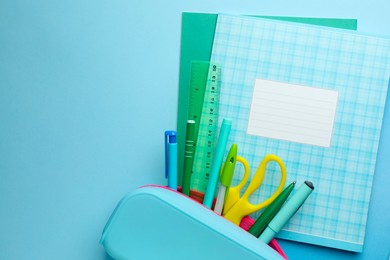 Photo of Copybooks and other school stationery on light blue background, flat lay. Space for text