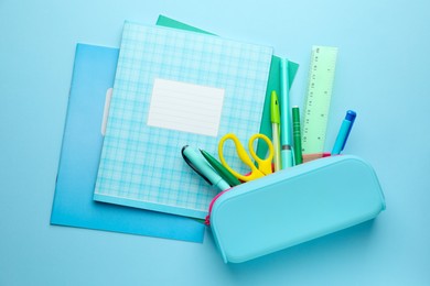 Photo of Copybooks and other school stationery on light blue background, flat lay