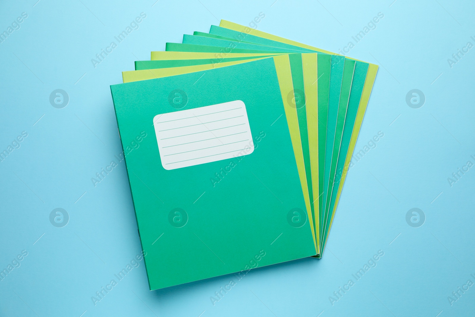 Photo of Colorful copybooks on light blue background, top view