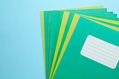 Photo of Colorful copybooks on light blue background, top view. Space for text