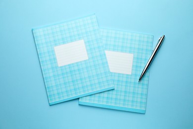 Photo of Two copybooks and pen on light blue background, top view