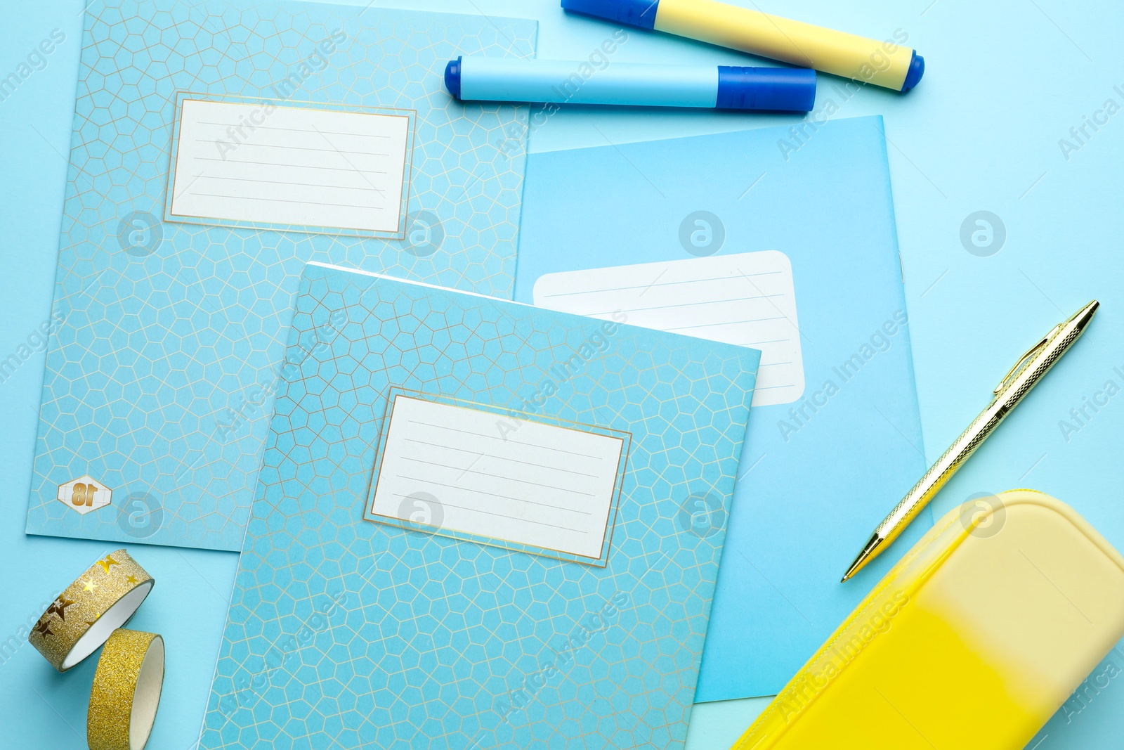 Photo of Copybooks and other school stationery on light blue background, flat lay