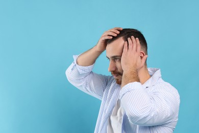 Photo of Baldness problem. Man with receding hairline on light blue background, space for text