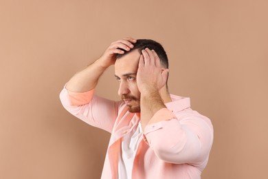 Baldness problem. Man with receding hairline on beige background