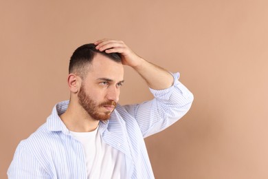 Baldness problem. Man with receding hairline on beige background, space for text