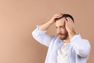 Baldness problem. Man with receding hairline on beige background, space for text