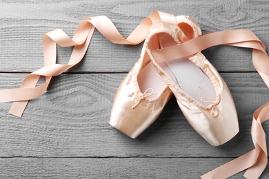 Photo of Pair of beautiful pointe shoes on grey wooden table, top view