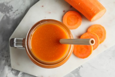 Photo of Fresh carrot juice in mason jar and vegetable on gray table, top view