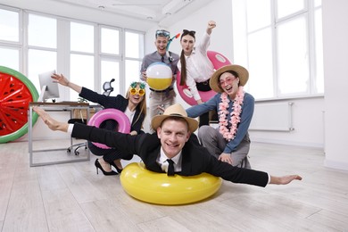 Photo of Happy coworkers with different beach accessories having fun in office, low angle view