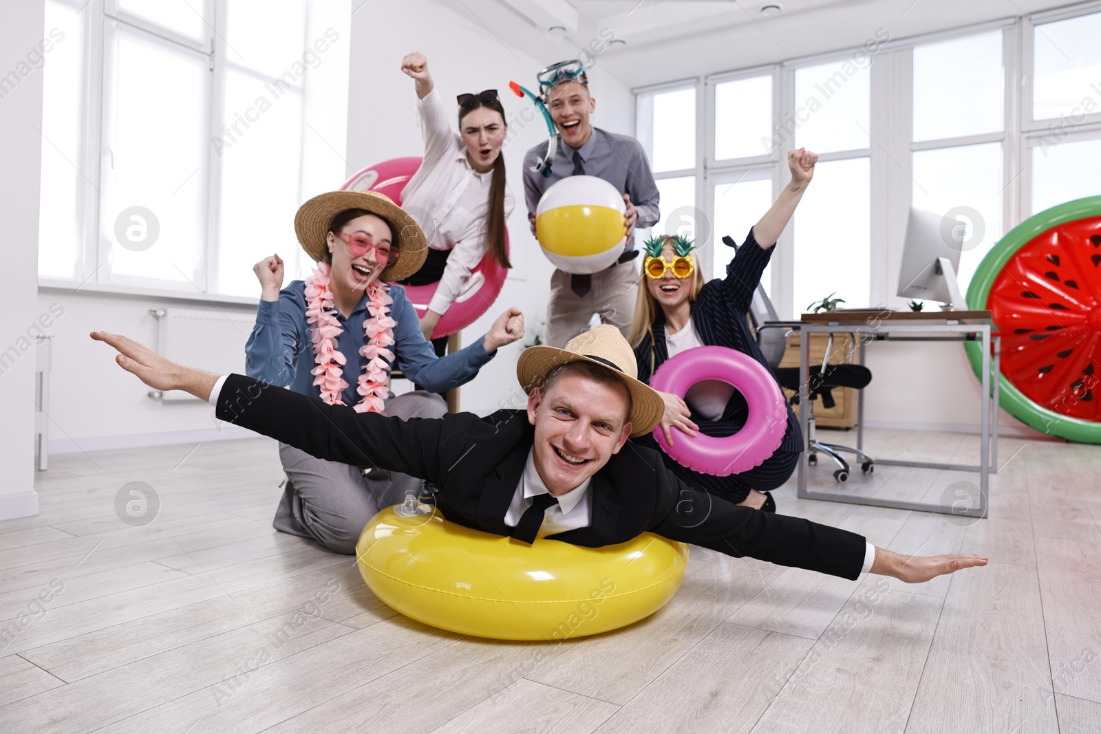 Photo of Happy coworkers with different beach accessories having fun in office, low angle view