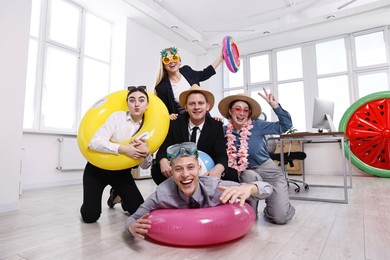 Happy coworkers with different beach accessories having fun in office, low angle view