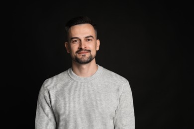 Portrait of handsome middle aged man on black background, space for text