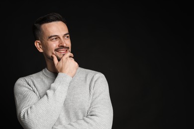 Portrait of handsome middle aged man on black background, space for text