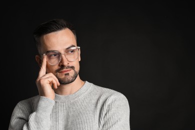 Portrait of handsome middle aged man on black background, space for text