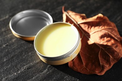 Photo of Natural solid perfume and dry leaf on black table, closeup