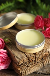 Photo of Natural solid perfume and pink roses on wooden table, closeup