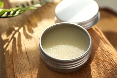 Photo of Natural solid perfume in container on wood, closeup