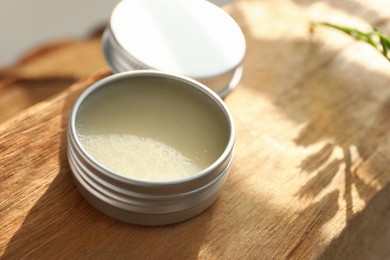 Photo of Natural solid perfume in container on wood, closeup