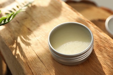 Photo of Natural solid perfume in container on wood, closeup