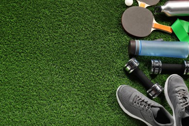 Photo of Different sports equipment on artificial grass, flat lay. Space for text