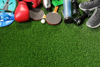 Photo of Different sports equipment on artificial grass, above view. Space for text