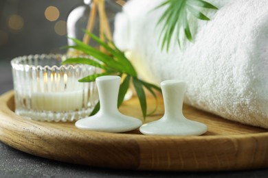 Photo of Spa stones, burning candle, towel and green leaves on grey table, closeup