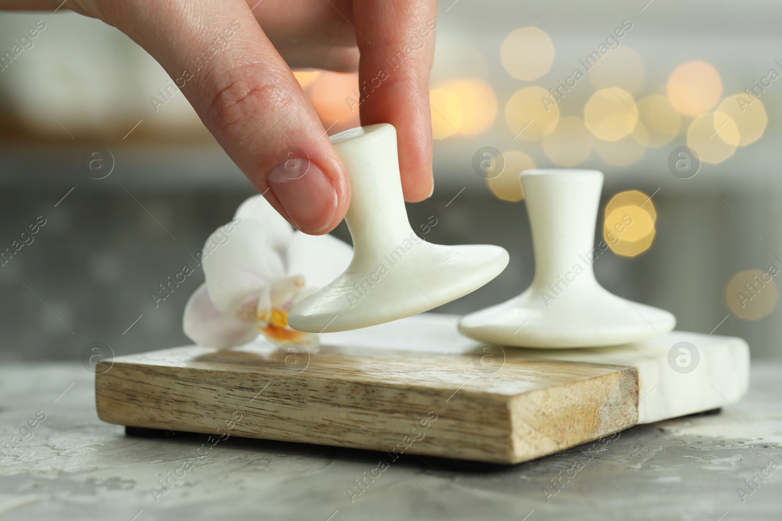 Photo of Woman with spa stone at grey table, closeup