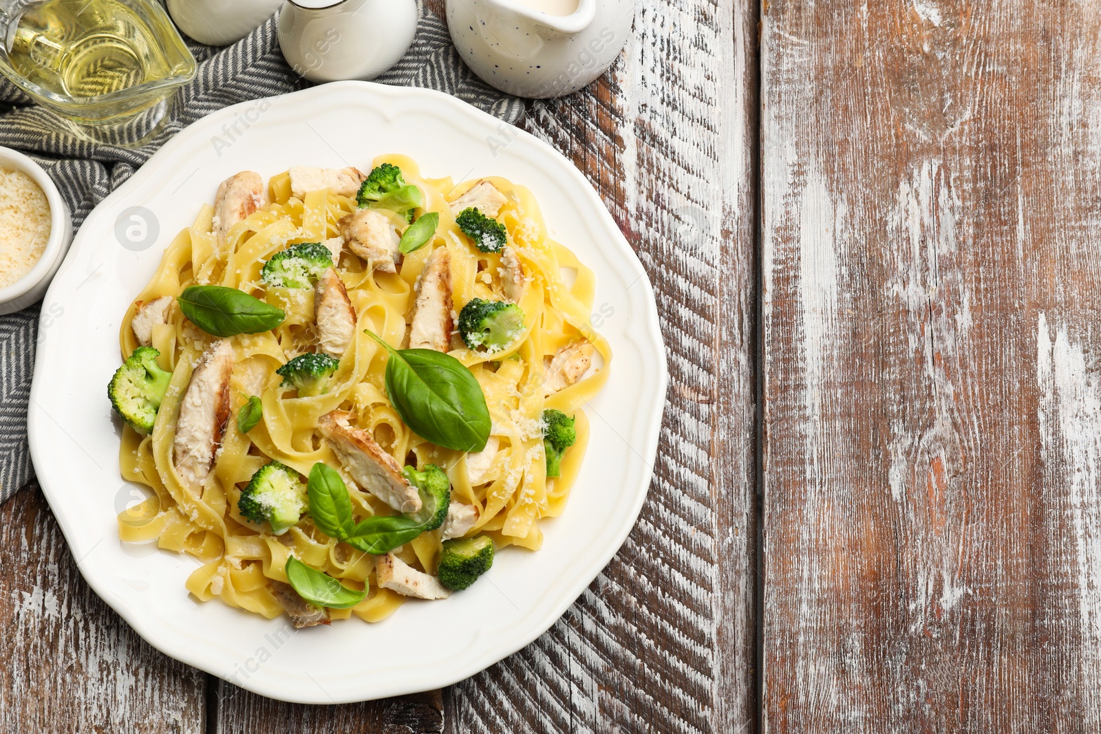 Photo of Delicious pasta Alfredo with chicken served on wooden table, flat lay. Space for text