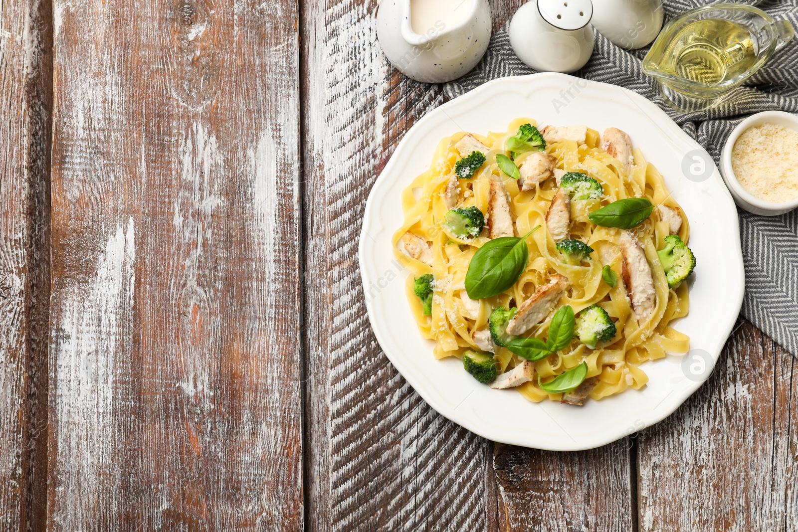 Photo of Delicious pasta Alfredo with chicken served on wooden table, flat lay. Space for text