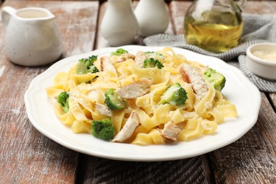 Photo of Delicious pasta Alfredo with chicken served on wooden table, closeup