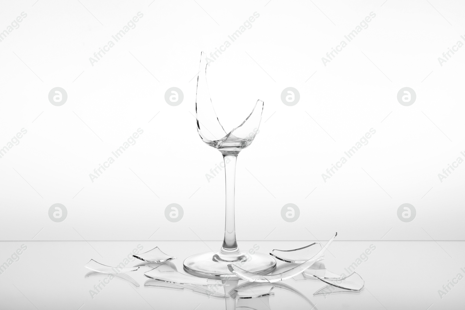 Photo of Pieces of broken wine glass on white background