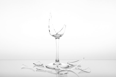 Photo of Pieces of broken wine glass on white background