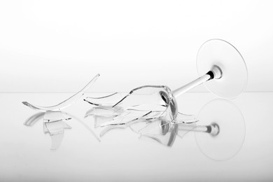 Photo of Pieces of broken wine glass on white background