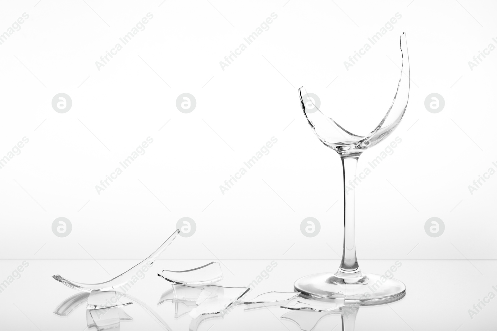 Photo of Pieces of broken wine glass on white background