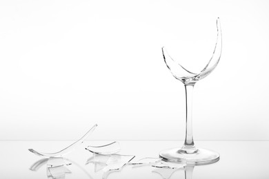 Photo of Pieces of broken wine glass on white background