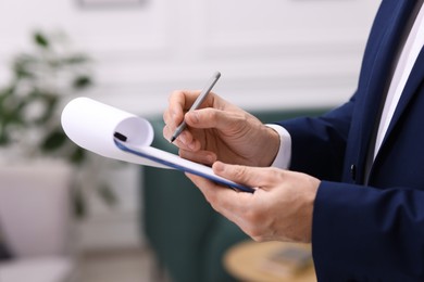 Photo of Real estate appraisal. Inspector with clipboard conducting property valuation indoors, closeup