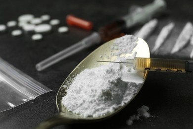 Photo of Drug addiction. Spoon with powder and syringe on gray textured table, closeup