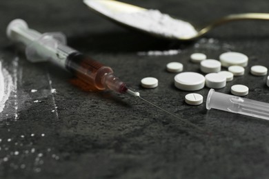 Photo of Drug addiction. Syringe, pills and spoon with powder on gray textured table, closeup