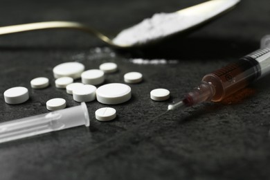 Photo of Drug addiction. Syringe, pills and spoon with powder on gray textured table, closeup