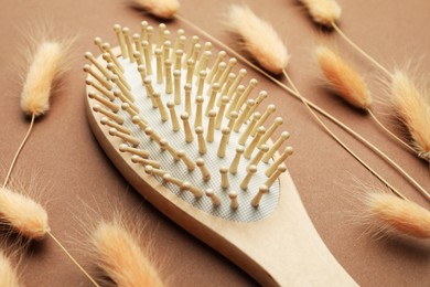 Photo of Wooden hair brush and spikes on brown background, closeup