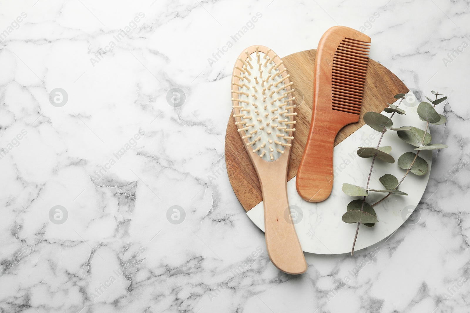 Photo of Hair brush, comb and eucalyptus on white marble background, top view. Space for text