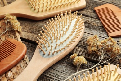 Photo of Hair brushes, combs and dried flowers on wooden background, closeup