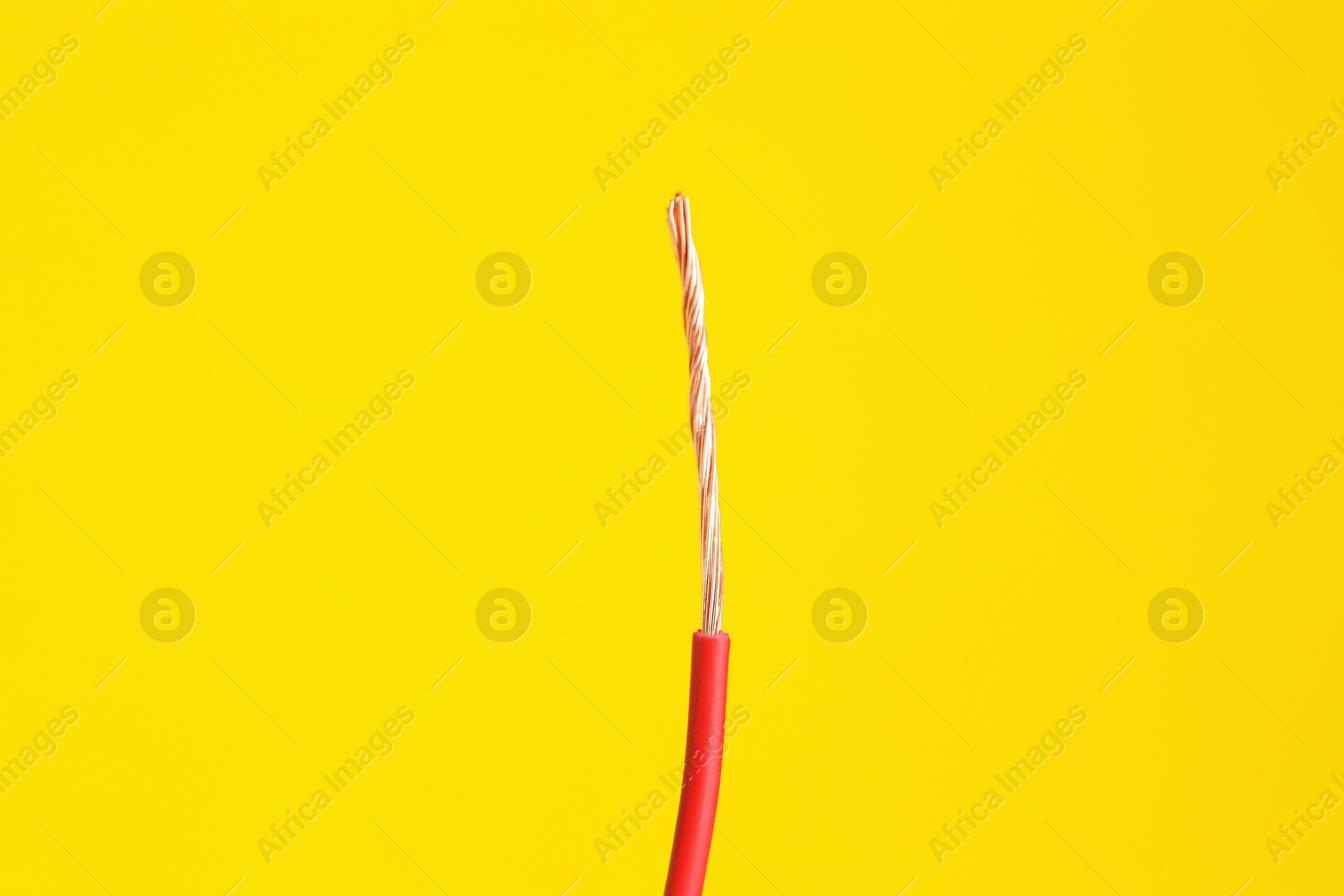 Photo of Red stripped electrical wire on yellow background, closeup