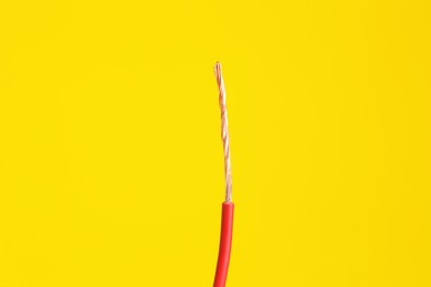 Photo of Red stripped electrical wire on yellow background, closeup