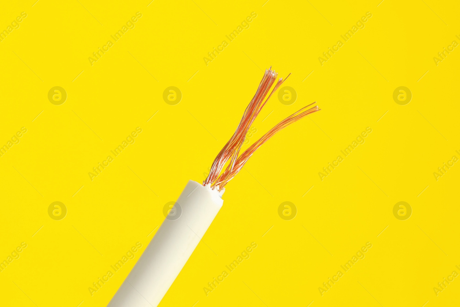 Photo of White stripped electrical wire on yellow background, closeup