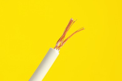 Photo of White stripped electrical wire on yellow background, closeup