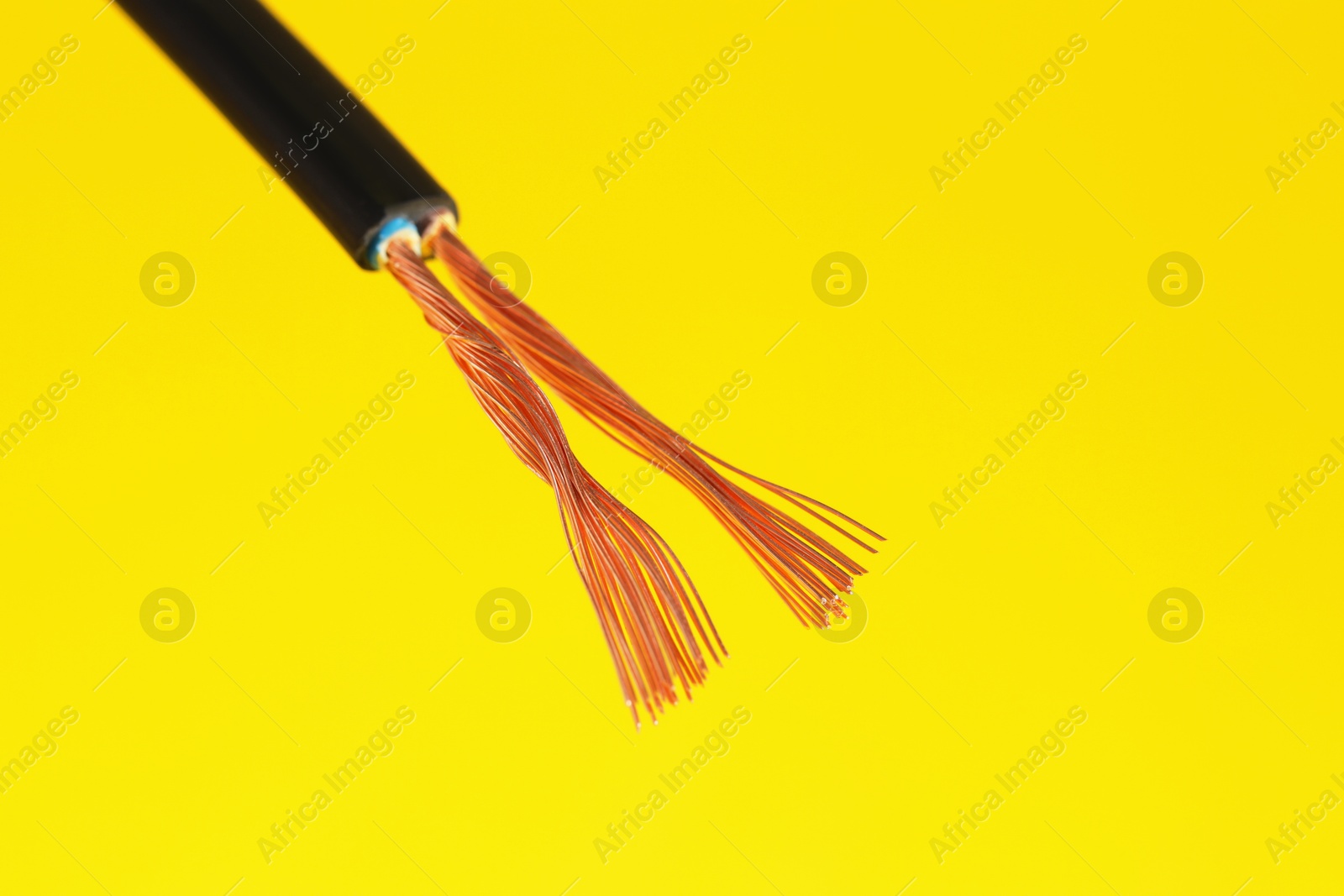 Photo of Black stripped electrical wire on yellow background, closeup