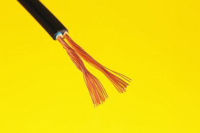 Photo of Black stripped electrical wire on yellow background, closeup