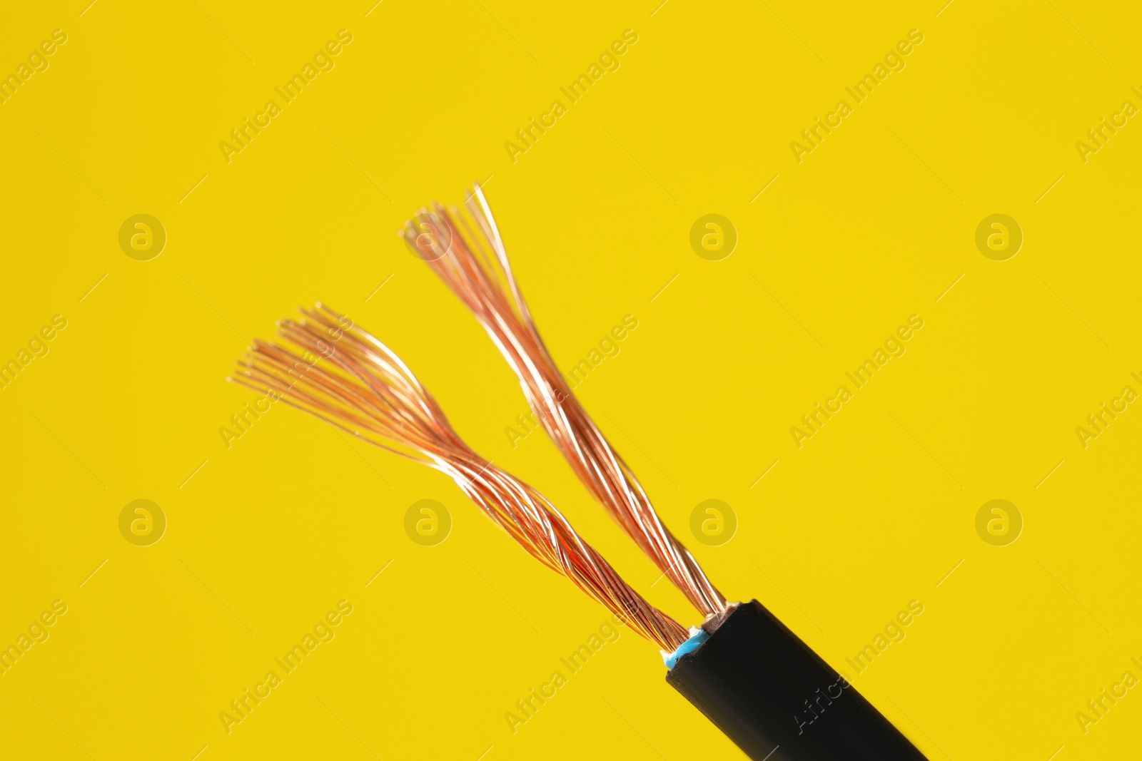 Photo of Black stripped electrical wire on yellow background, closeup